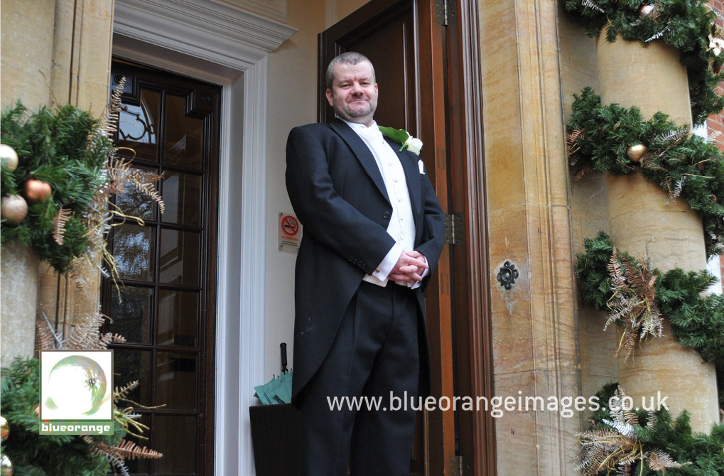 The bridegroom at the main entrance to Hunton Park wedding venue, Herts